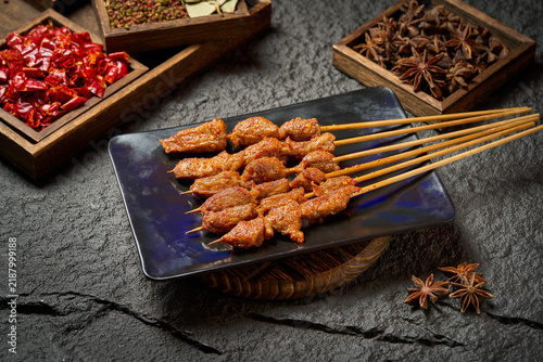 фотографія spicy grilled meat skewers on dark plate with chili peppers and star anise