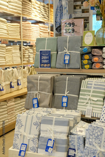 Neatly arranged bed linens, towels and home textile products displayed on shelves in a modern home goods store. Interior of a retail shop with household essentials for sale