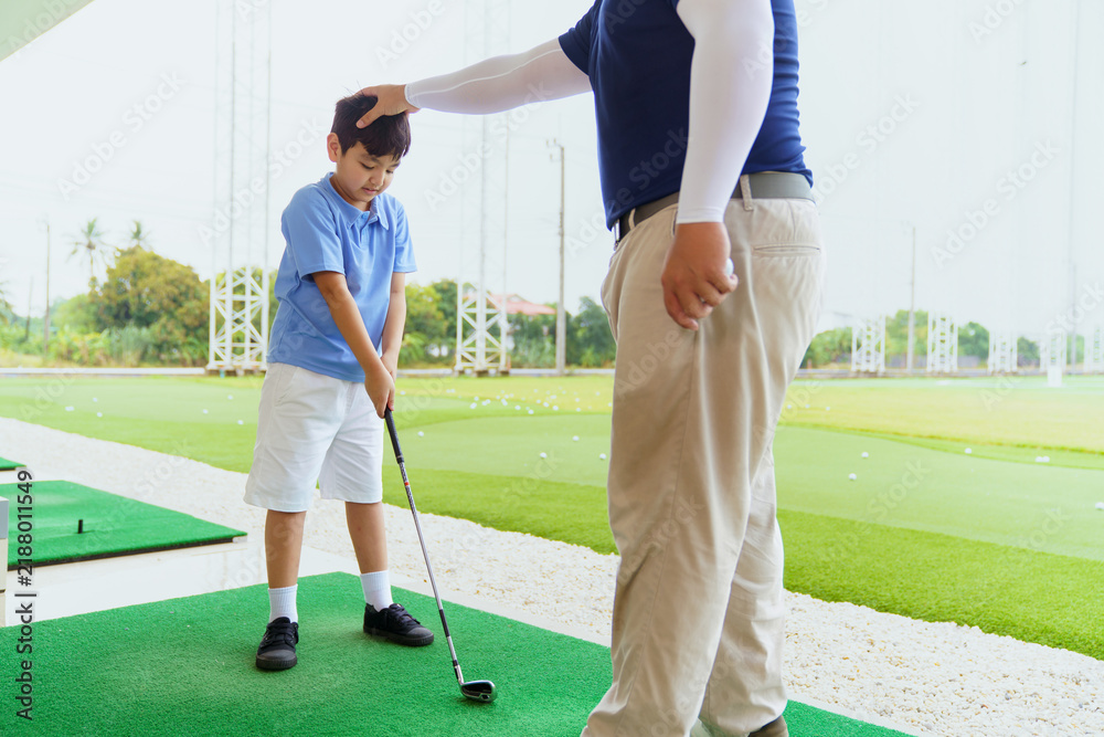 Obraz premium Golf instructor teaching basic stance and setup to young Asian boy