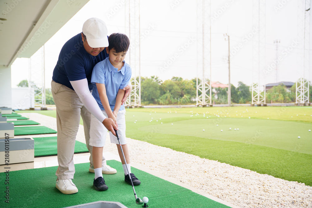 Obraz premium Golf instructor teaching basic stance and setup to young Asian boy