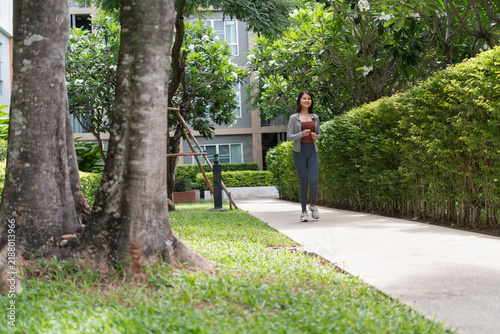 Obraz na plátně Asian Gen Z woman jogging alone in green urban park promoting wellness healthy lifestyle and sustainable city concept