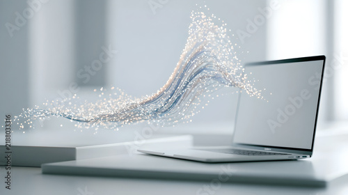 A laptop sits on a white desk with glowing abstract data streams flowing from the screen with abstract digital particles