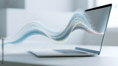A laptop computer displaying an abstract blue light wave flowing out from the open screen with particles emerging screen