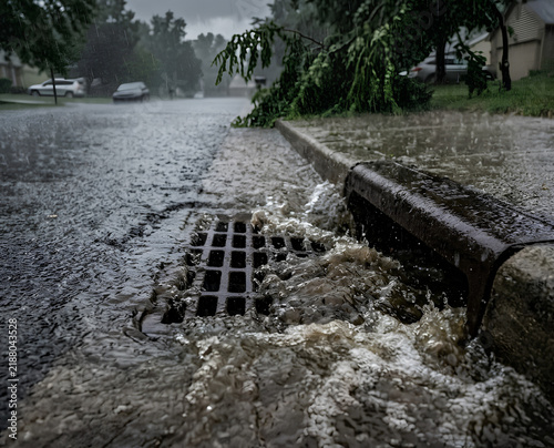 Heavy rain water flooding a street storm drain in the city