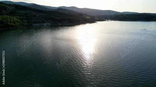 Beautiful aerial footage of Lake during sunset, featuring warm golden reflections on steel-blue water and dark Beskid mountains against a colorful sky.