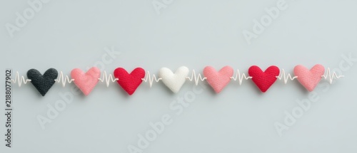 Colorful heart shapes symbolizing love and emotion against a soft gray background with a heartbeat line