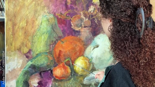 close-up of a painting and female artist paints an autumn still life with pumpkins