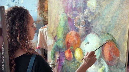 Teenage artist in college painting class, art studio, art workshop. She paints still life on canvas with oil paint.