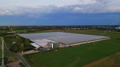 Cinematic aerial view of a massive industrial greenhouse for sustainable food production in a rural landscape.