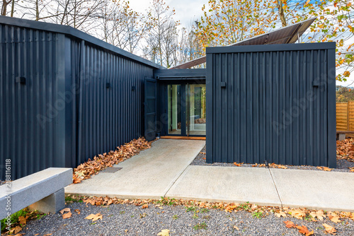 Modern modular coworking office built with shipping containers features dark corrugated exterior and solar panels, blending contemporary design with sustainable building in natural autumn environment