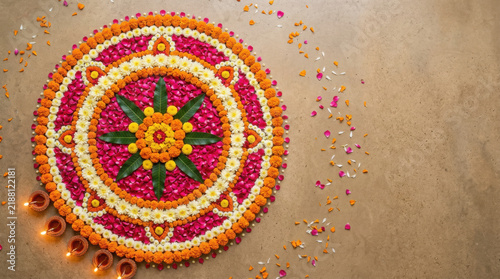 Vibrant floral rangoli with orange and pink flower petals and lit clay diyas on generated using ai