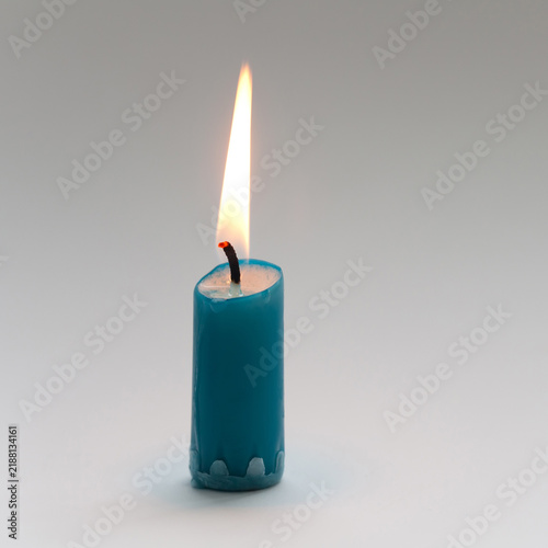 Short turquoise candle stub, tall flame. Cozy home concept, warm mood poster, interior banner