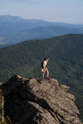 woman standing on top of a mountain on rocks