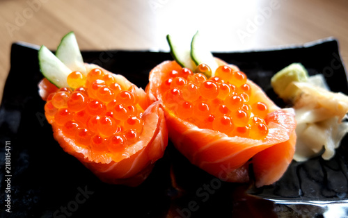 Delicious Japanese salmon roe gunkan maki sushi garnished with cucumber and wasabi.