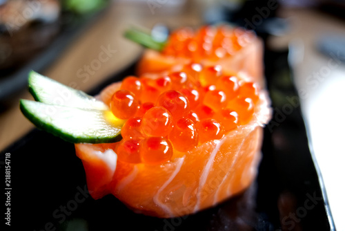 Delicious Japanese salmon roe gunkan maki sushi garnished with cucumber and wasabi.