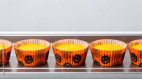 Festively Decorated Halloween Cupcakes in Orange Wrappers on a Baking Tray Ready for Decoration
