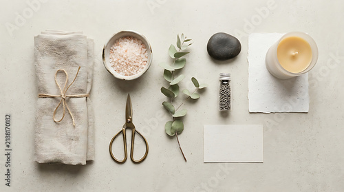 Minimalist lifestyle composition featuring beige linen napkins, metal craft scissors, fragrant eucalyptus sprigs and candle wax