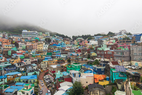 Obraz na plátně Dense rows of colorful residential buildings cover a hillside beneath low clouds and thick fog