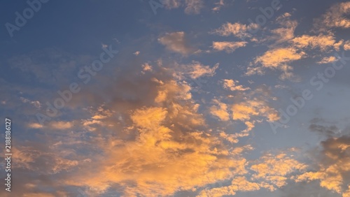 Vibrant golden orange clouds glow beautifully against a blue evening sky