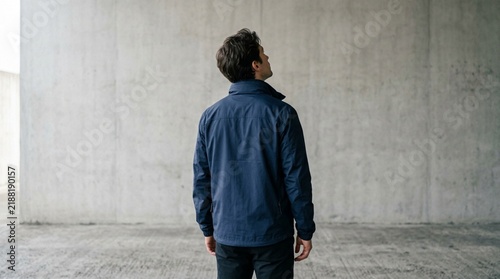 Visionary man looking up against industrial concrete wall hero image for website landing page, corporate leadership presentation background, and social media ad banner for lifestyle brands.