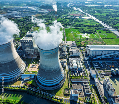 Canvastavla Aerial view of a thermal power plant with cooling towers emitting white steam under bright direct sunlight