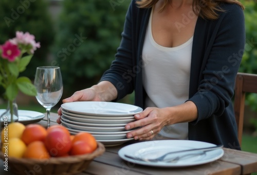 Woman unloading dishes from picnic table.