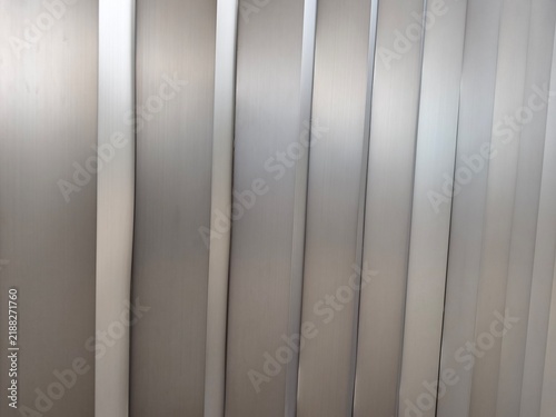 Foto Close-up architectural detail of brushed stainless steel wall cladding panels featuring repetitive vertical geometric zigzag ridges casting dramatic shadow depth