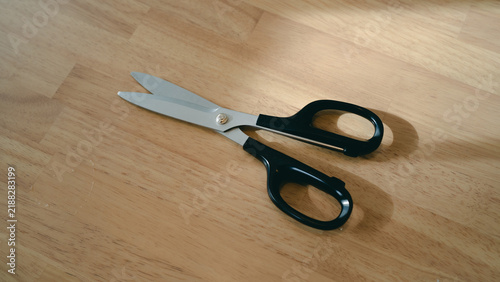 Black handled scissors on a wooden table