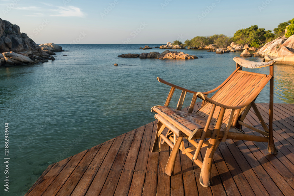 Fototapeta premium Wooden armchair at resort patio by sea at sunrise, Ko Man Klang, Rayong