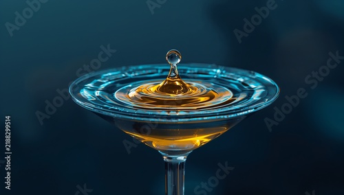 Water drop splashing into a glass of amber liquid