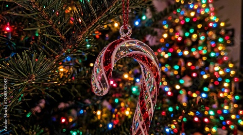 Red and white candy cane ornament hanging on a decorated christmas tree
