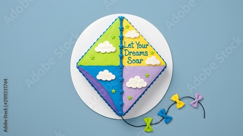 Kite shaped sheet cake with clouds and inspirational text on a plate