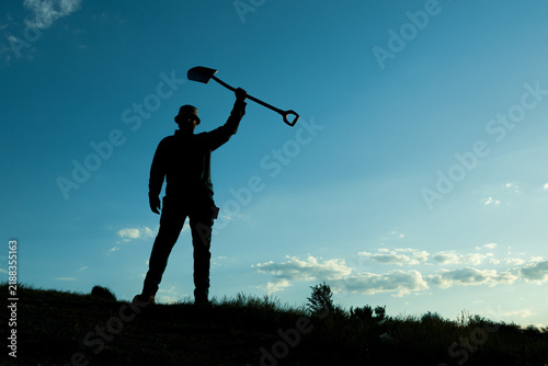 Victory Pose, Man Raising Shovel Skyward in Celebration
