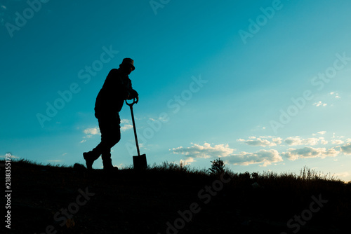 Foto Man in a Hat Resting on His Shovel in Quiet Contemplation