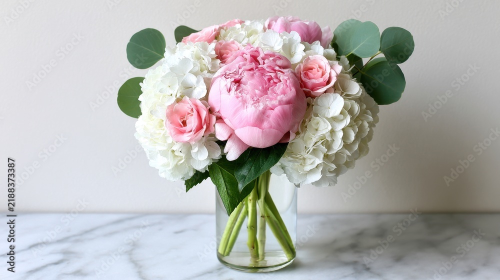 Obraz premium Elegant Pink Peony and White Hydrangea Floral Arrangement in Glass Vase on Marble Surface for Home Decor or Event Styling Ideas