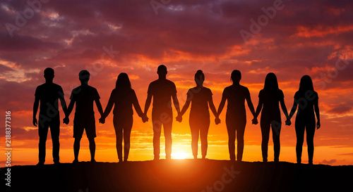 Silhouette of people holding hands together at dramatic sunset unity community concept photo