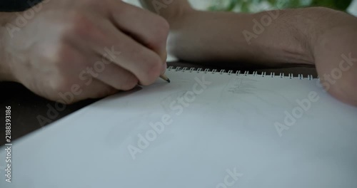 Male hand draw a drawing on sheet of paper. 4K 10-bit
