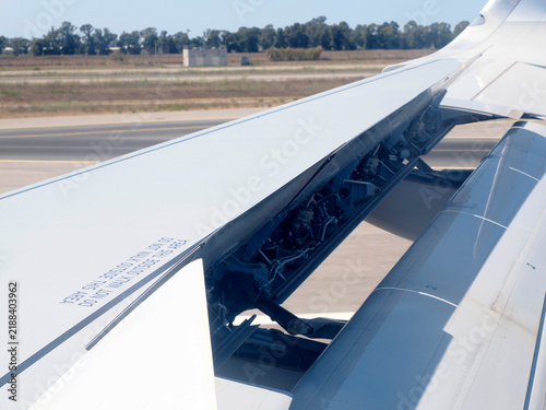 Foto Airplane Wing With Extended Flaps During landing Roll Over Runway At Airport