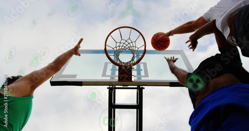 Reaching two players contesting basket at park court, in athletic gear and holding orange ball