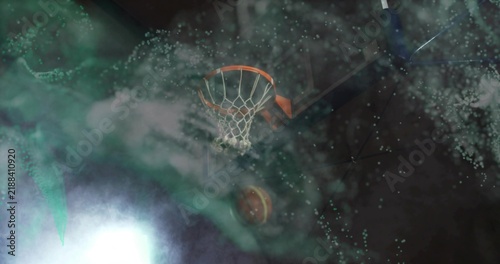 Swooping basketball passing upward through rim and net in dark studio, with spotlight and smoke