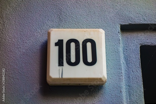 Obraz na płótnie White house number sign with 100 on textured wall