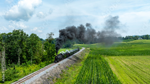 Fotografie Steam Locomotive Travels Through Lush Countryside Under a Clear Blue Sky
