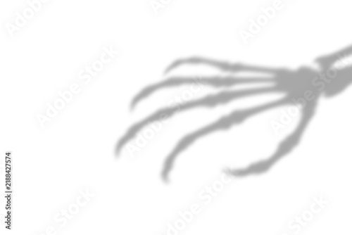Foto A dark blurry shadow of a creepy skeleton hand reaching out cast on a plain whit