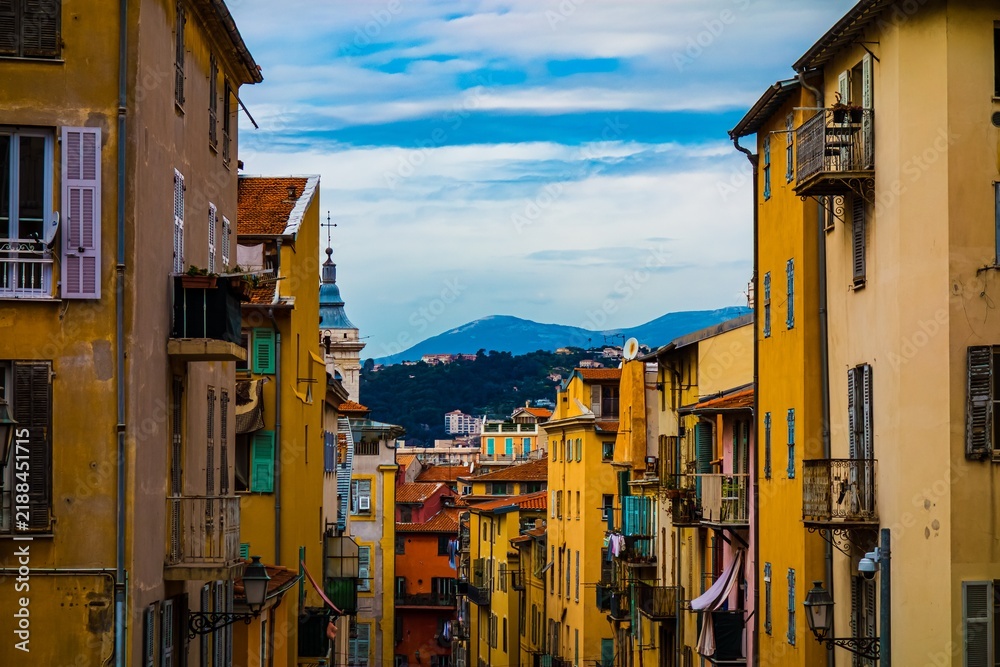 Fototapeta premium Colorful buildings on a narrow street with mountains in the background