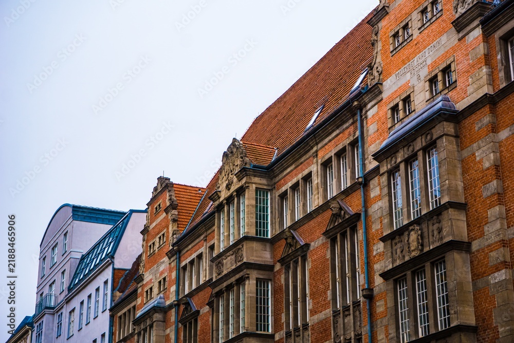 Obraz premium Ornate brick buildings with tiled roofs against a pale sky