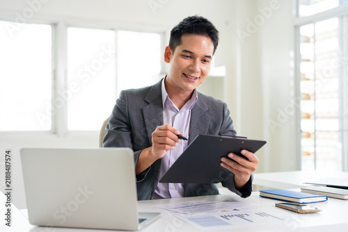 Young man in an office setting reviews documents attentively.