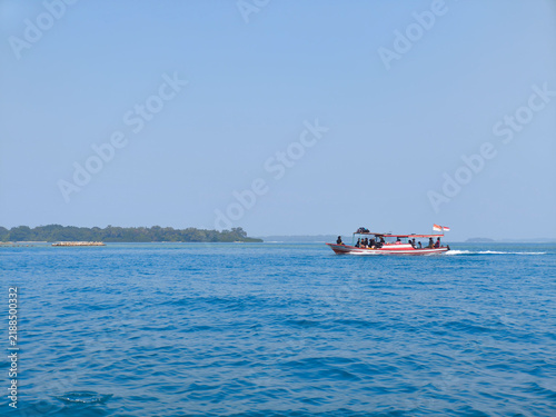 Obraz na płótnie Jakarta, Indonesia  September 5, 2026 Traditional wooden boat carrying passengers sailing across blue ocean waters in Kepulauan Seribu