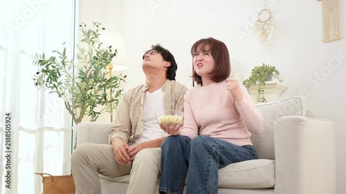 Couple Enjoys Movie Time at Home With Snacks and Laughter on a Cozy Sofa