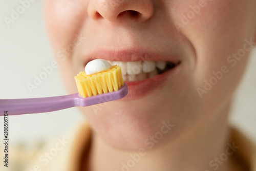 Obraz na płótnie Young woman brushing her teeth at home, close-up of daily oral hygiene and dental care routine