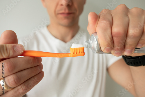 Fotografie Young man brushing his teeth with a toothbrush at home, daily oral hygiene and dental care routine